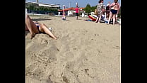 Une femme expose sa chatte sous une culotte sur une plage publique