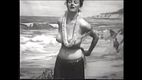La giocosa signora con grandi meloni si toglie il vestito hawaiano e mostra il suo culo rotondo sulla spiaggia