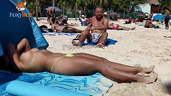 Oben-ohne-Sonnenbaden am Strand, um von anderen Männern beobachtet zu werden